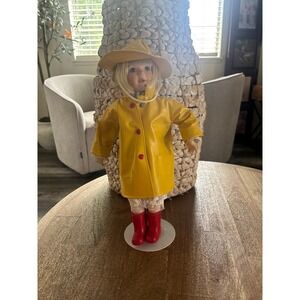 Porcelain Doll with Yellow raincoat and red boots.